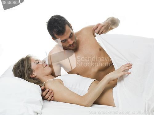 Image of funny couple foreplaying in a white bed and sheets