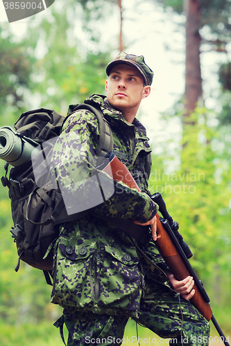 Image of young soldier or hunter with gun in forest