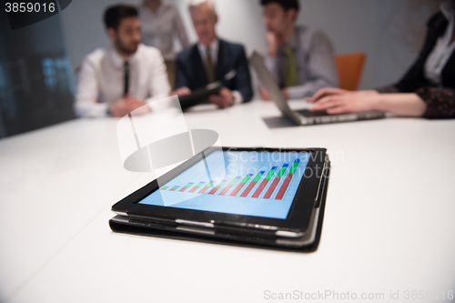 Image of close up of touchpad with analytics documents at business meetin