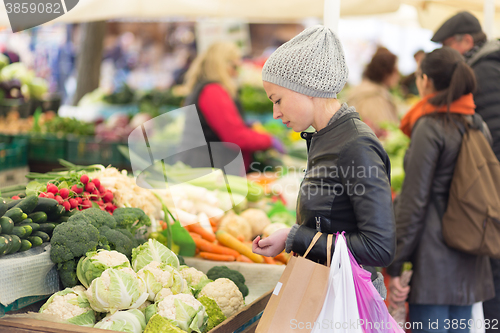 Image of Woman buying vegetable at local food market. 