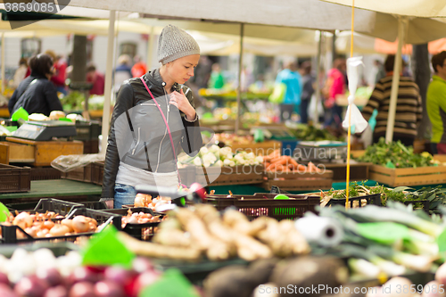 Image of Woman buying vegetable at local food market. 