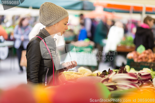 Image of Woman buying vegetable at local food market. 