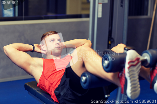 Image of young man making abdominal exercises in gym