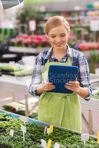 Image of happy woman with tablet pc in greenhouse