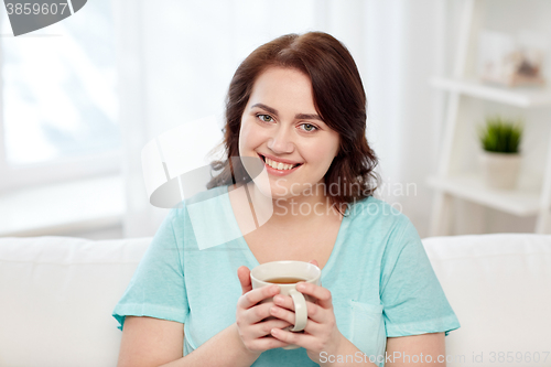 Image of happy plus size woman with cup of tea at home