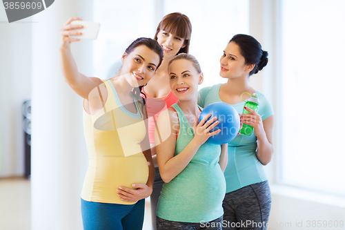 Image of pregnant women taking selfie by smartphone in gym