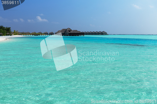 Image of bungalow huts in sea water on exotic resort beach