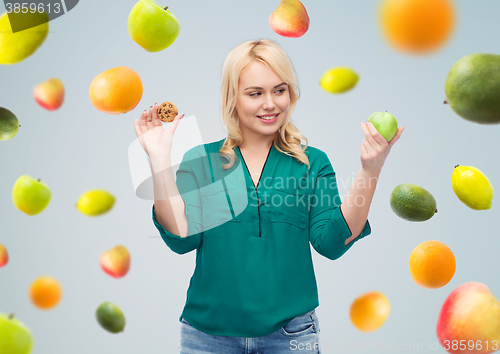 Image of smiling woman choosing between apple and cookie