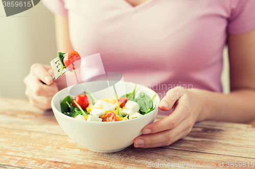 Image of close up of young woman eating salad at home
