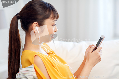 Image of happy asian woman with smartphone and earphones