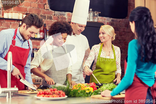 Image of happy friends and chef cook cooking in kitchen
