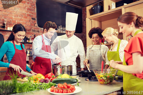 Image of happy friends and chef cook cooking in kitchen