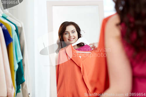 Image of happy plus size woman with shirt at mirror