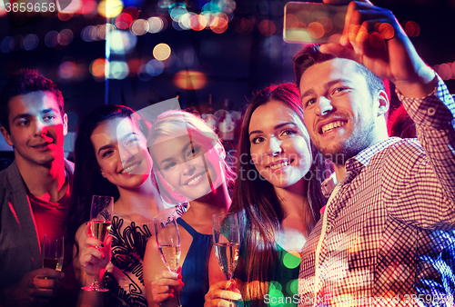 Image of friends taking selfie by smartphone in night club