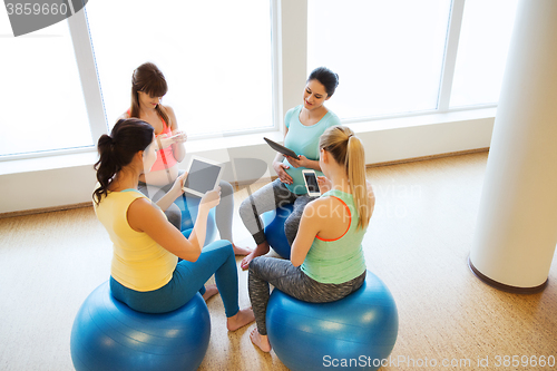 Image of happy pregnant women with gadgets in gym
