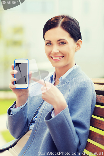 Image of young smiling businesswoman showing smartphone