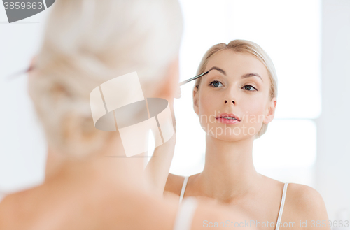 Image of woman with brush doing eyebrow makeup at bathroom