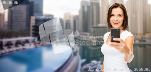 Image of woman taking picture by smartphone over dubai city
