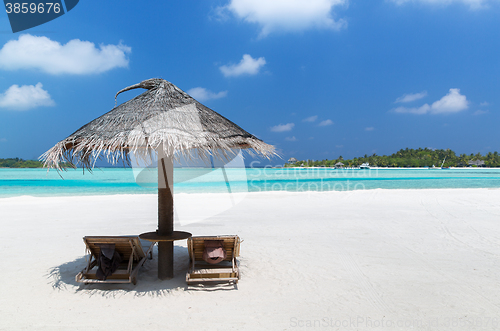 Image of palapa and sunbeds by sea on maldives beach