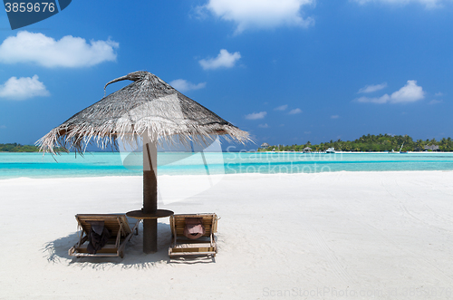 Image of palapa and sunbeds by sea on maldives beach