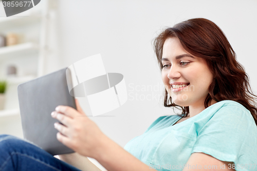 Image of happy young plus size woman with tablet pc at home