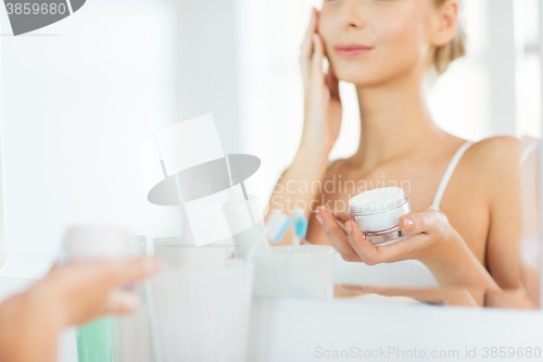 Image of close up of woman applying face cream at bathroom