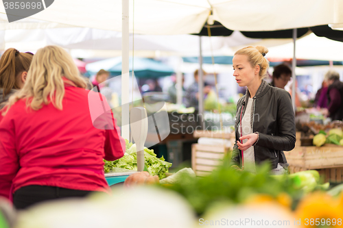 Image of Woman buying vegetable at local food market. 