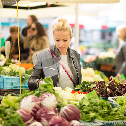 Image of Woman buying vegetable at local food market. 