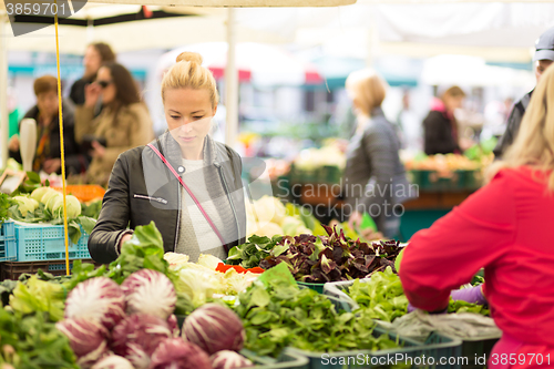 Image of Woman buying vegetable at local food market. 