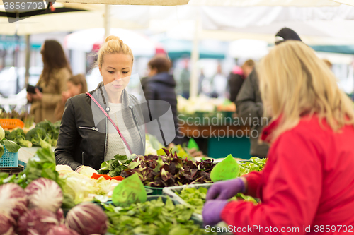 Image of Woman buying vegetable at local food market. 