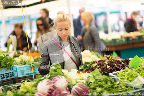 Image of Woman buying vegetable at local food market. 