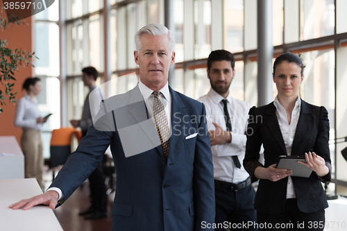 Image of portrait of senior businessman as leader  with group of people i