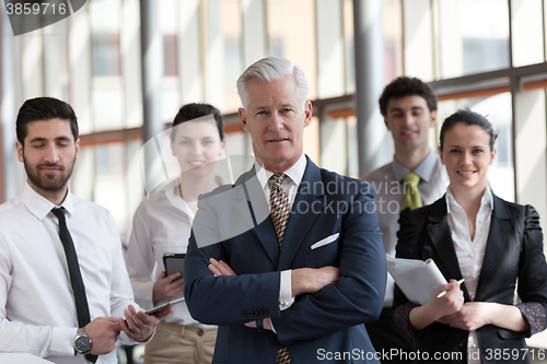 Image of portrait of senior businessman as leader  with group of people i