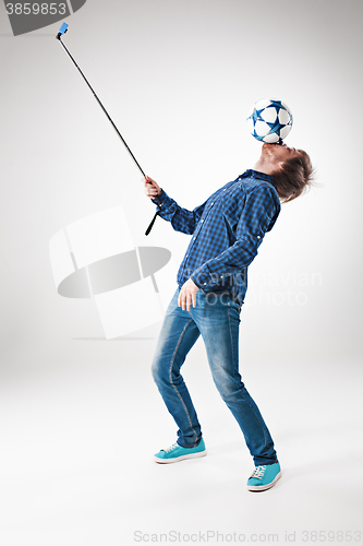 Image of The portrait of man with ball, holding selfie stick on white background