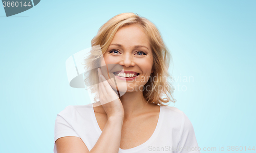 Image of smiling woman in white t-shirt touching her face