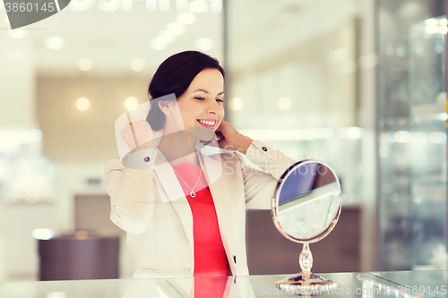 Image of happy woman choosing pendant at jewelry store