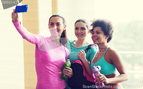 Image of happy women with smartphone taking selfie in gym