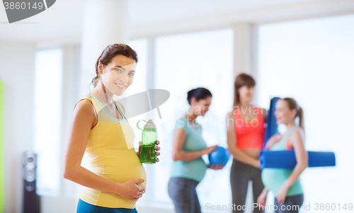 Image of happy pregnant woman with water bottle in gym