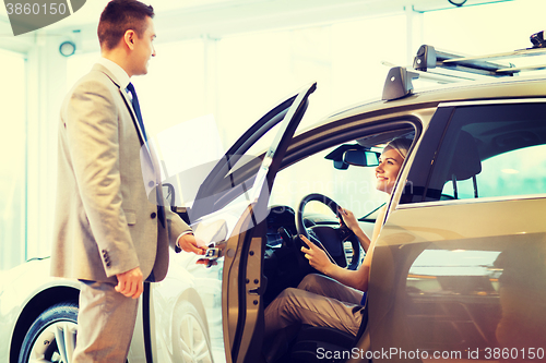 Image of happy woman with car dealer in auto show or salon