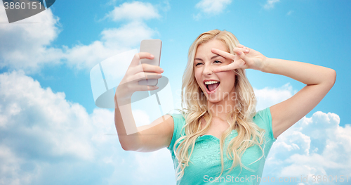 Image of smiling young woman taking selfie with smartphone