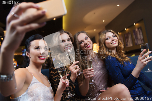 Image of women with champagne taking selfie at night club