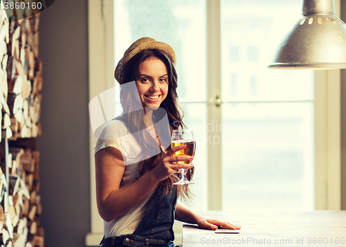 Image of happy young woman drinking beer at bar or pub