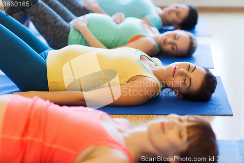 Image of happy pregnant women exercising on mats in gym