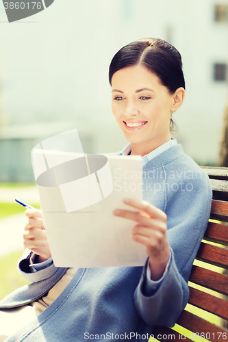 Image of smiling businesswoman reading papers outdoors