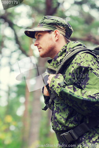 Image of young soldier with backpack in forest