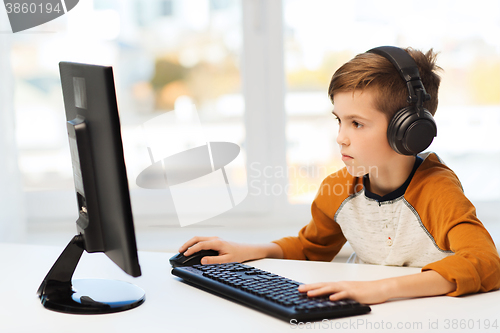 Image of boy with computer and headphones at home