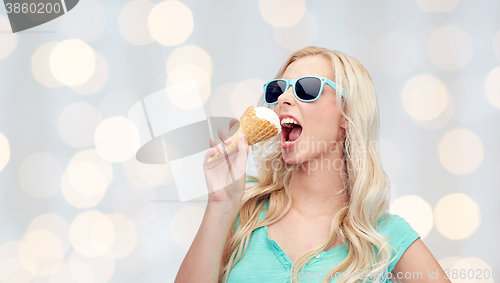 Image of happy young woman in sunglasses eating ice cream