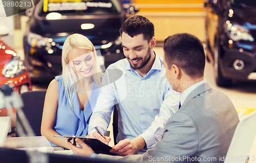 Image of happy couple with car dealer in auto show or salon