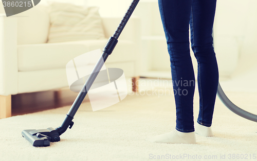 Image of close up of woman legs with vacuum cleaner at home