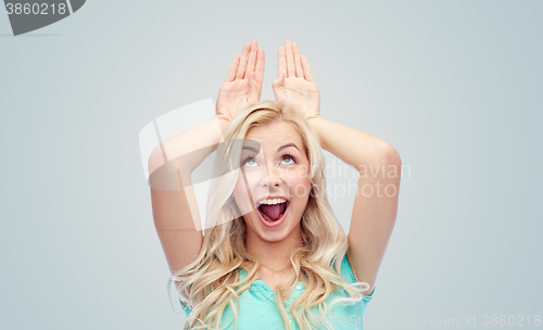 Image of happy smiling young woman making bunny ears